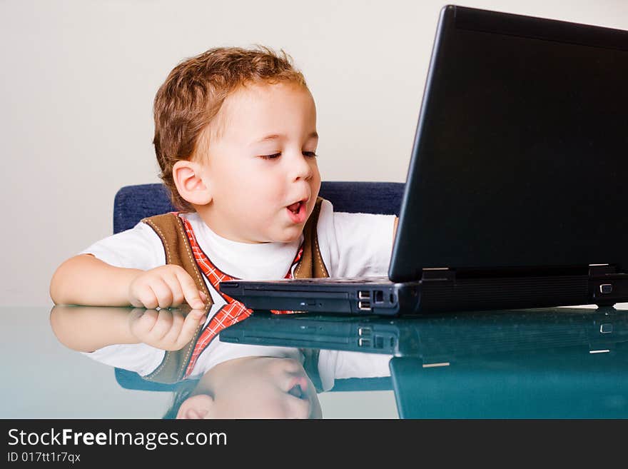 Small boy sitting at the table with laptop. Small boy sitting at the table with laptop