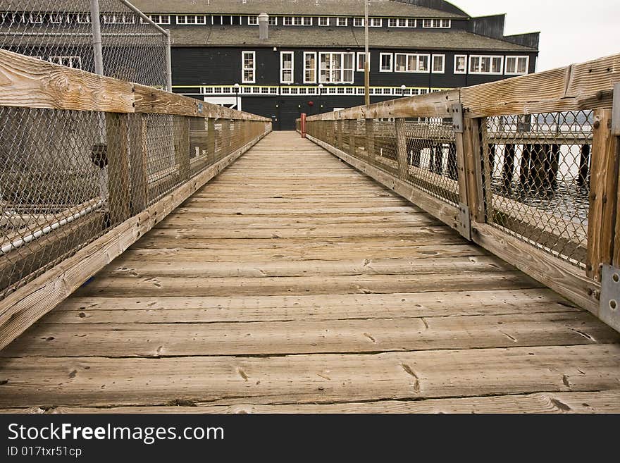 An old wooden plank walkway leading to a green coastal warehouse. An old wooden plank walkway leading to a green coastal warehouse