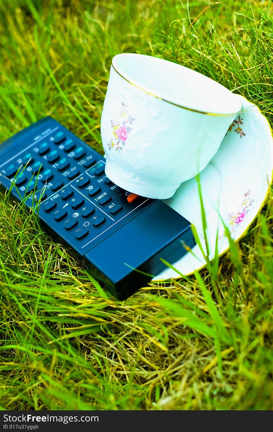 Photo of remote and cup on the grass. Photo of remote and cup on the grass