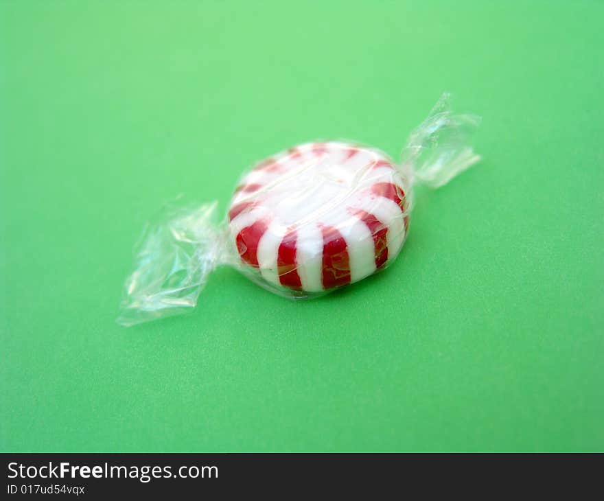 Red and white peppermint isolated over green background. Red and white peppermint isolated over green background