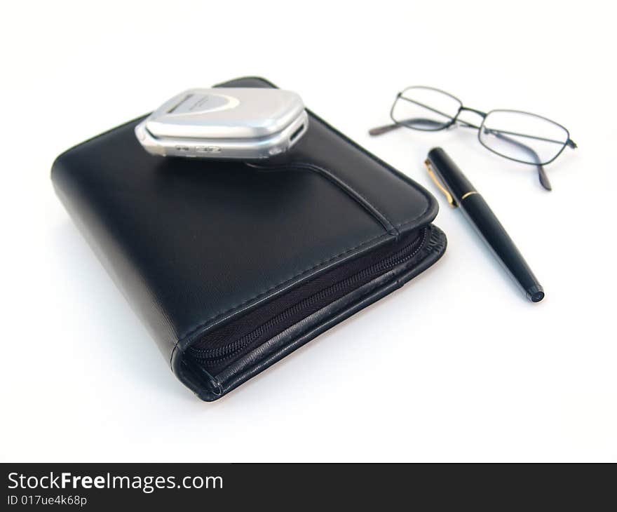 Black leather planner, pen, silver cell phone over white. Black leather planner, pen, silver cell phone over white