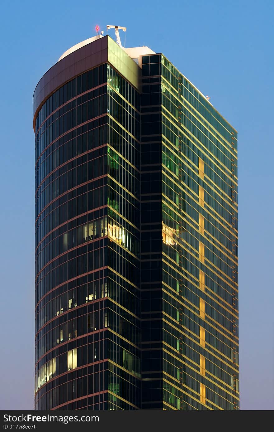 Blue mirrored walls of scyscraper with lights in Moscow (Russia) on the sunset