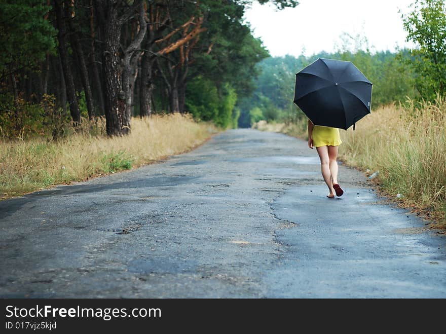 Young woman with black umbrella walking in park on a rainy day. Young woman with black umbrella walking in park on a rainy day