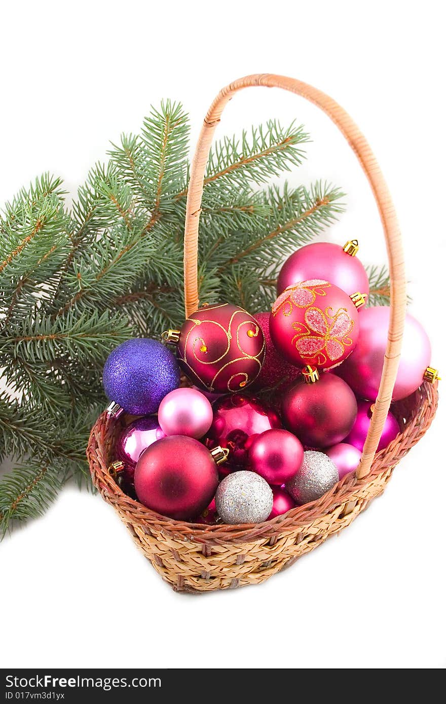 Yellow basket with New Year's spheres and green branch of fur-trees on white background