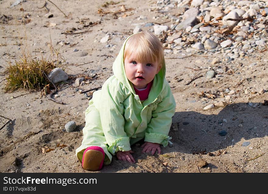 Babygirl play in sand on riverside