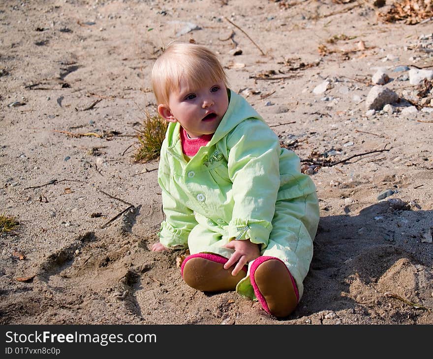 Baby sits on sand at autumn