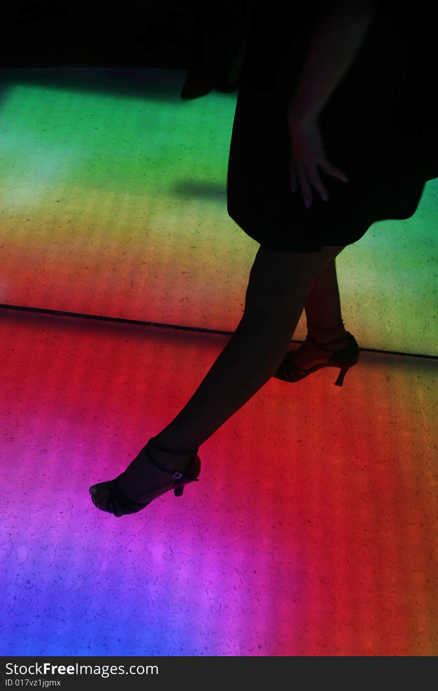 Colorfully lit dance floor, with human silhouettes in motion, dancing