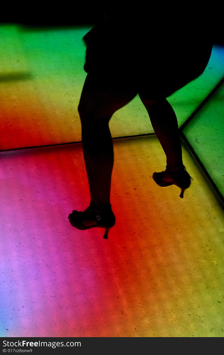 Colorfully lit dance floor, with human silhouettes in motion, dancing