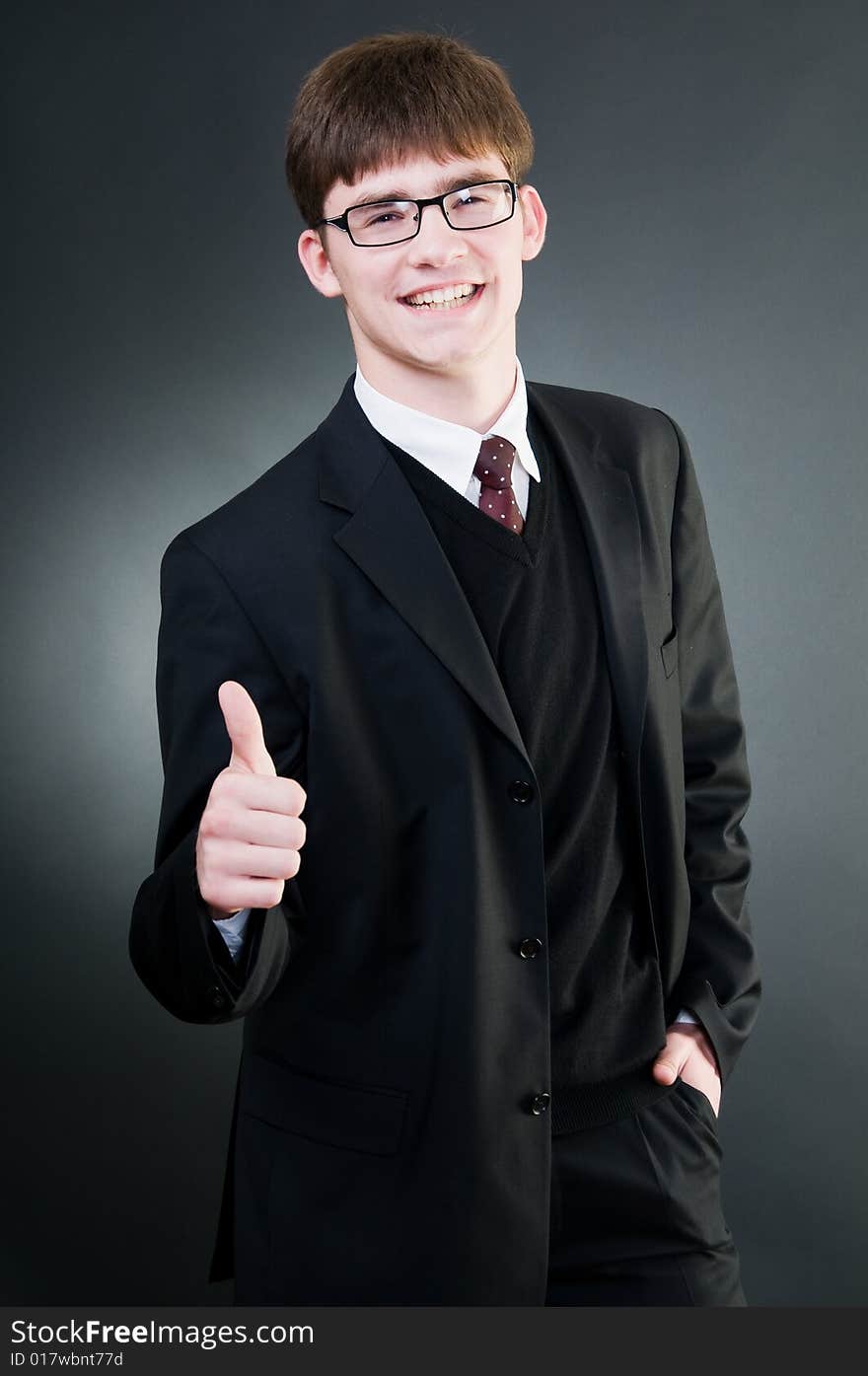 Young handsome businessman showing thumbs up, isolated on black background