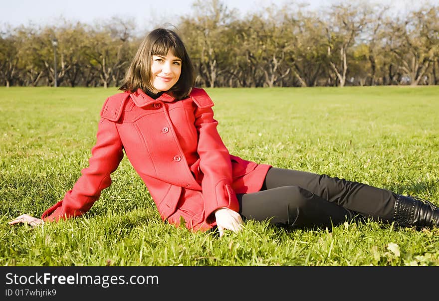 Young Woman Sitting On The Green Grass. Young Woman Sitting On The Green Grass