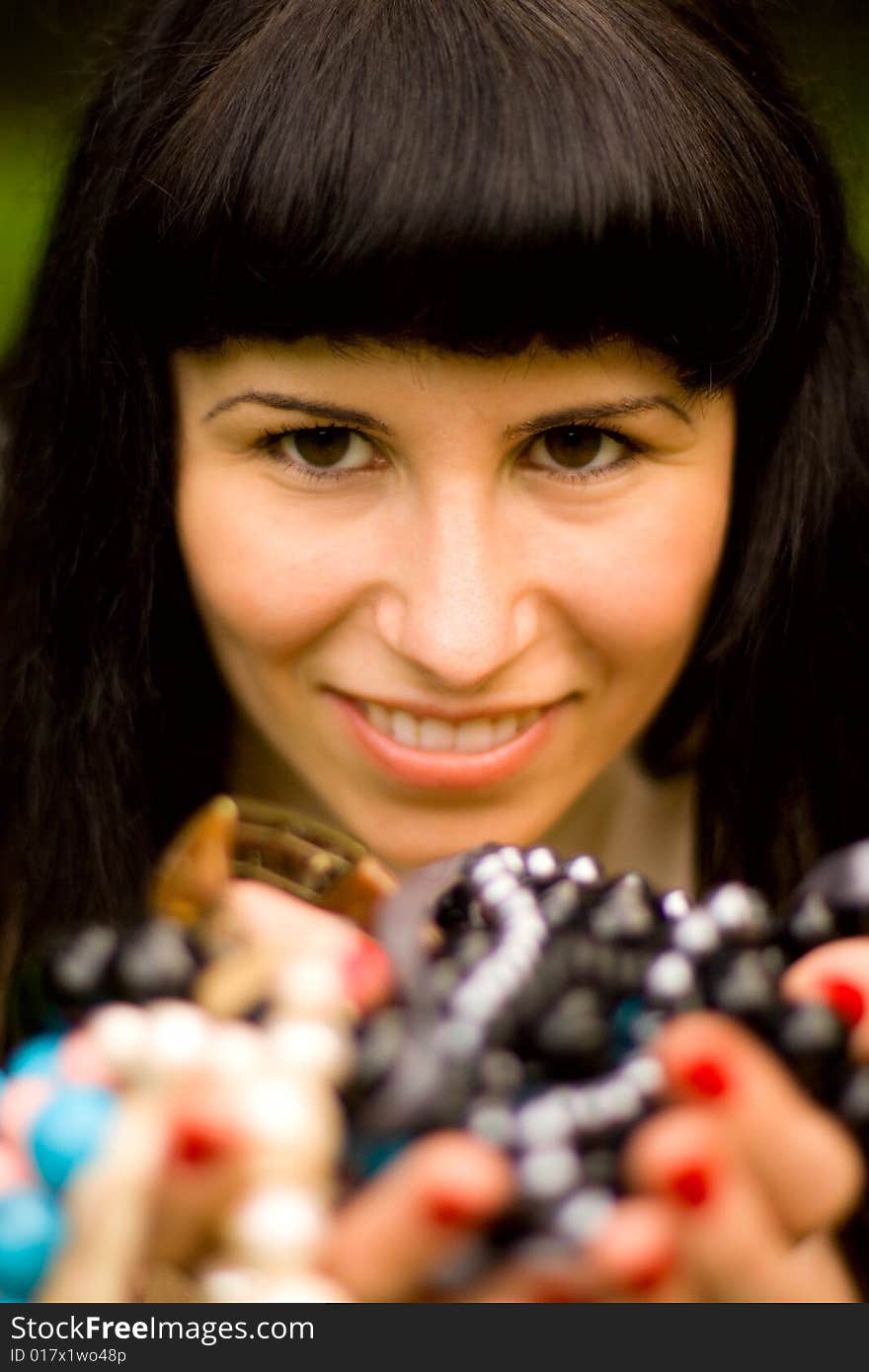 Closeup portrait on young brunette holding a lot of beads