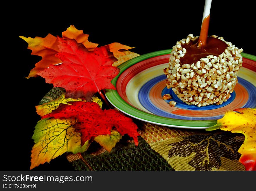 Single caramel apple in fall foliage. Single caramel apple in fall foliage.