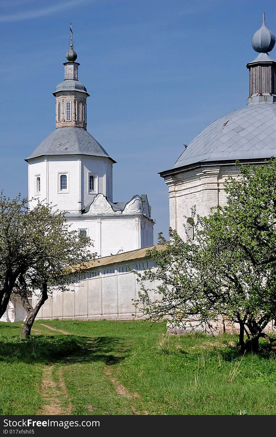 Tower and cathedral of orthodox monastery among apple trees garden  in russian province at sunny may day. Tower and cathedral of orthodox monastery among apple trees garden  in russian province at sunny may day