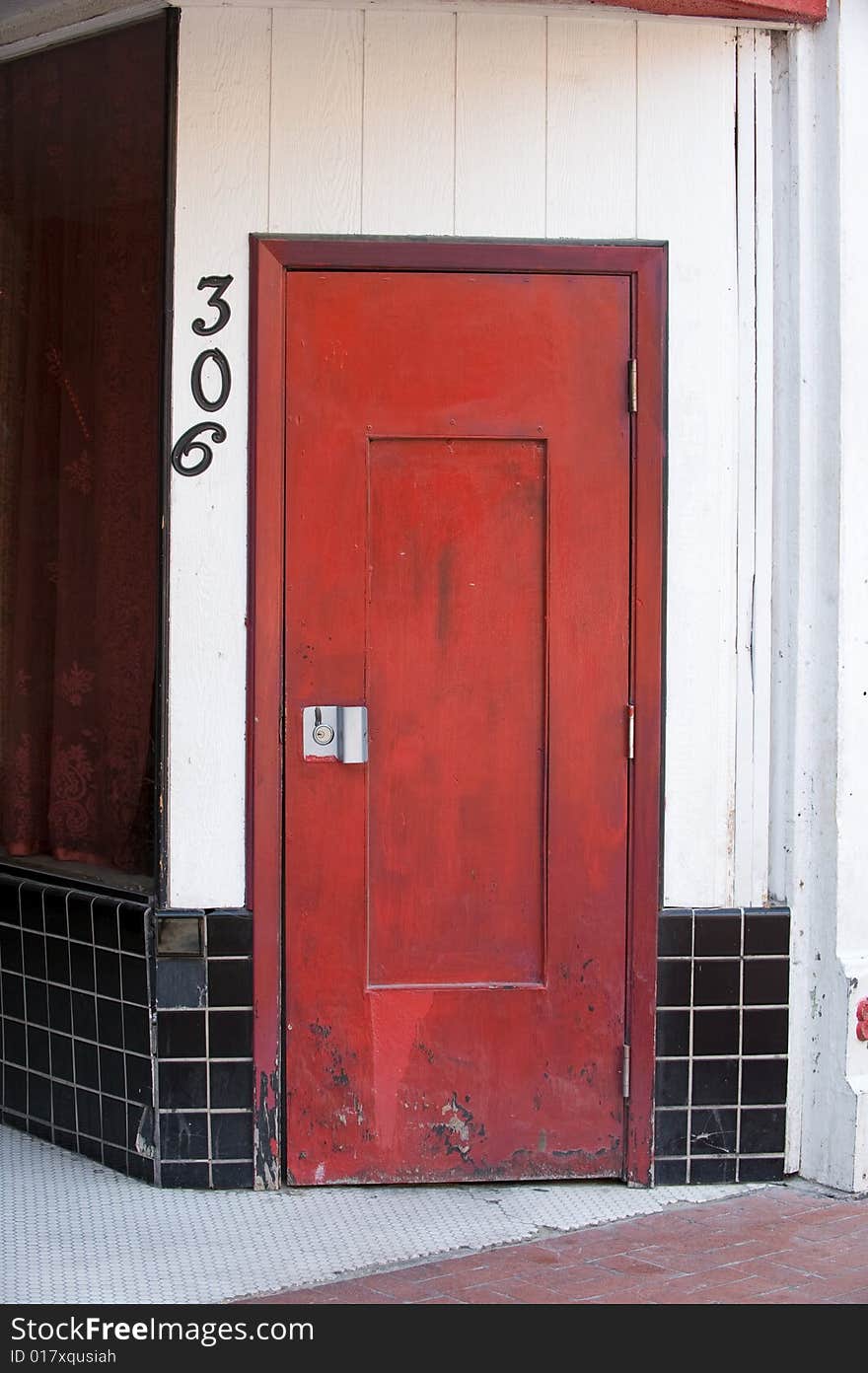 An image of a red wooden door with black tile