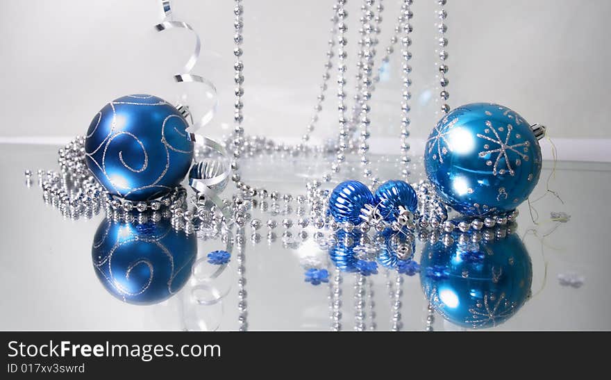 A lovely blue baubles on a mirror  surface with ribbons and beads. A lovely blue baubles on a mirror  surface with ribbons and beads.