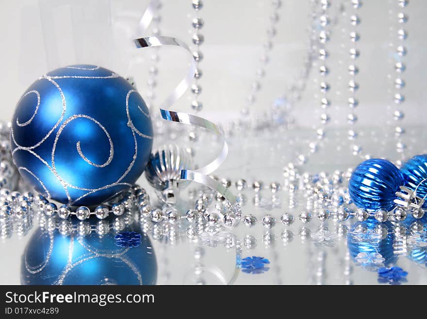 A lovely blue baubles on a mirror  surface with ribbons and beads. A lovely blue baubles on a mirror  surface with ribbons and beads.