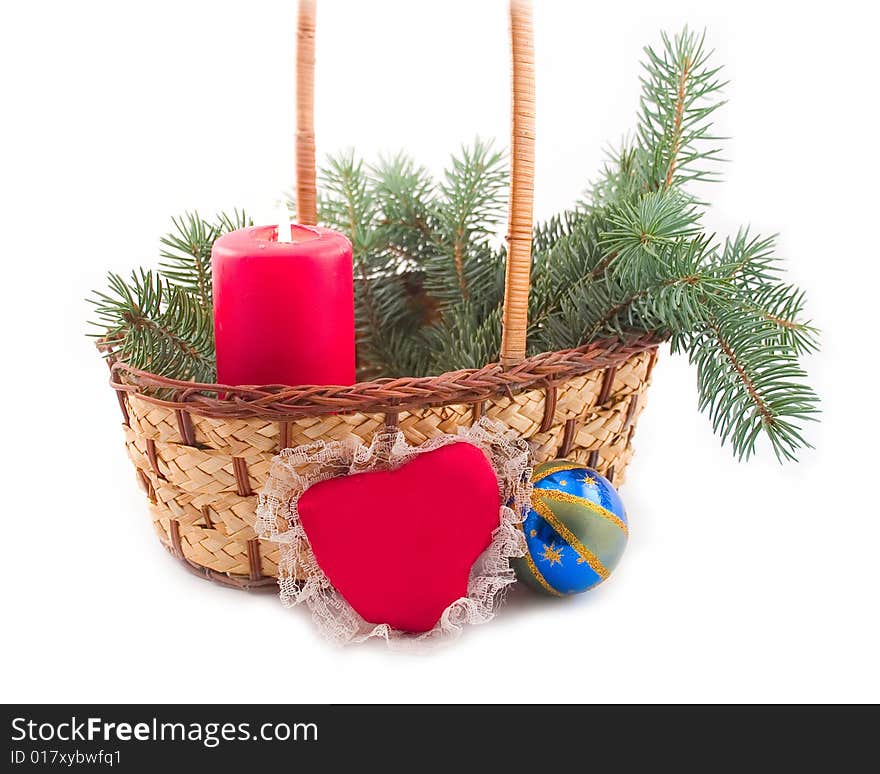 Red burning candle in yellow basket with green branch ate with blue New Year's sphere and red heart from silk on white background. Red burning candle in yellow basket with green branch ate with blue New Year's sphere and red heart from silk on white background