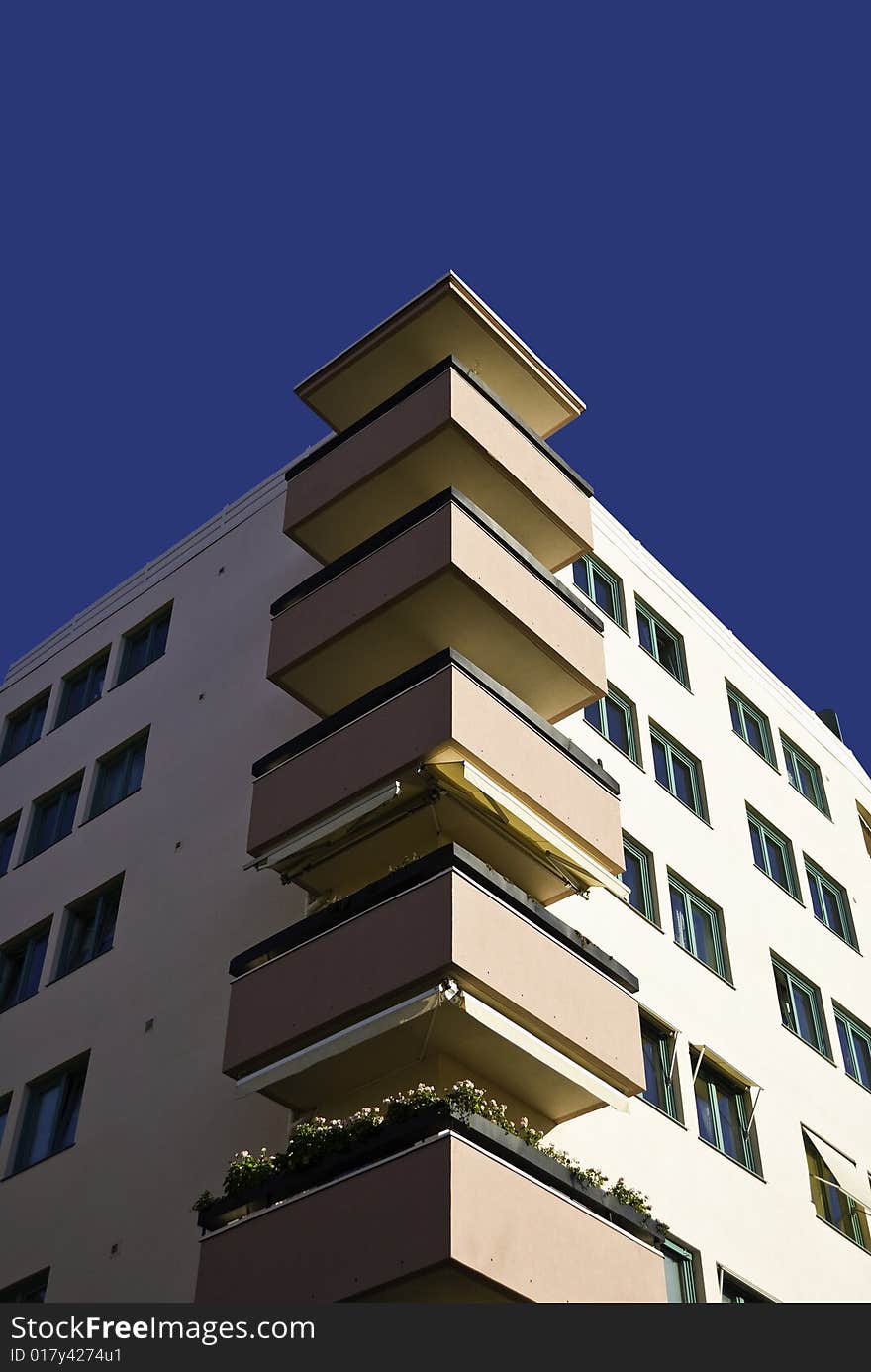 Apartments with pink balconies at the corners. Blue sky.