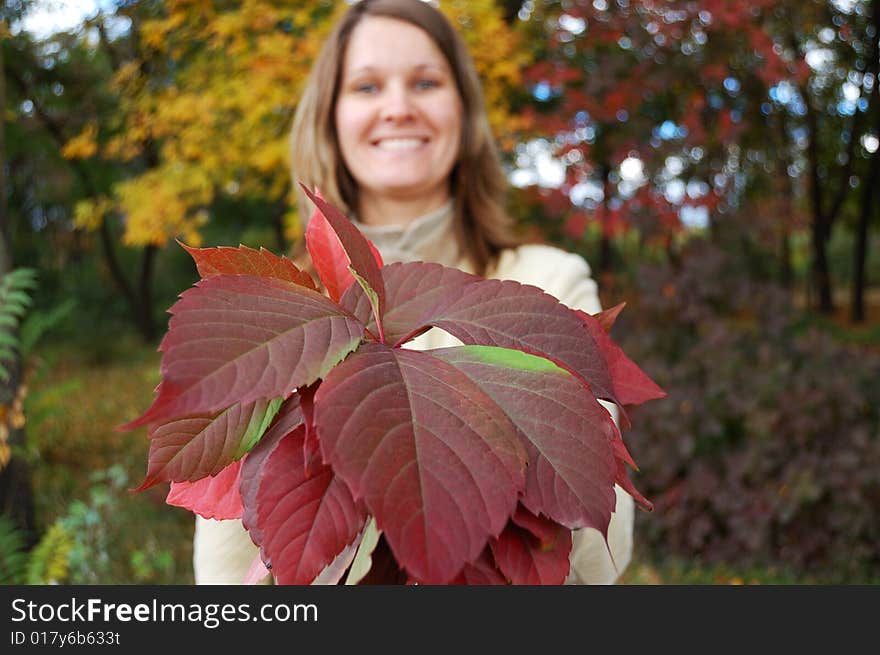 Young woman holds bouquet of autumnal leaves