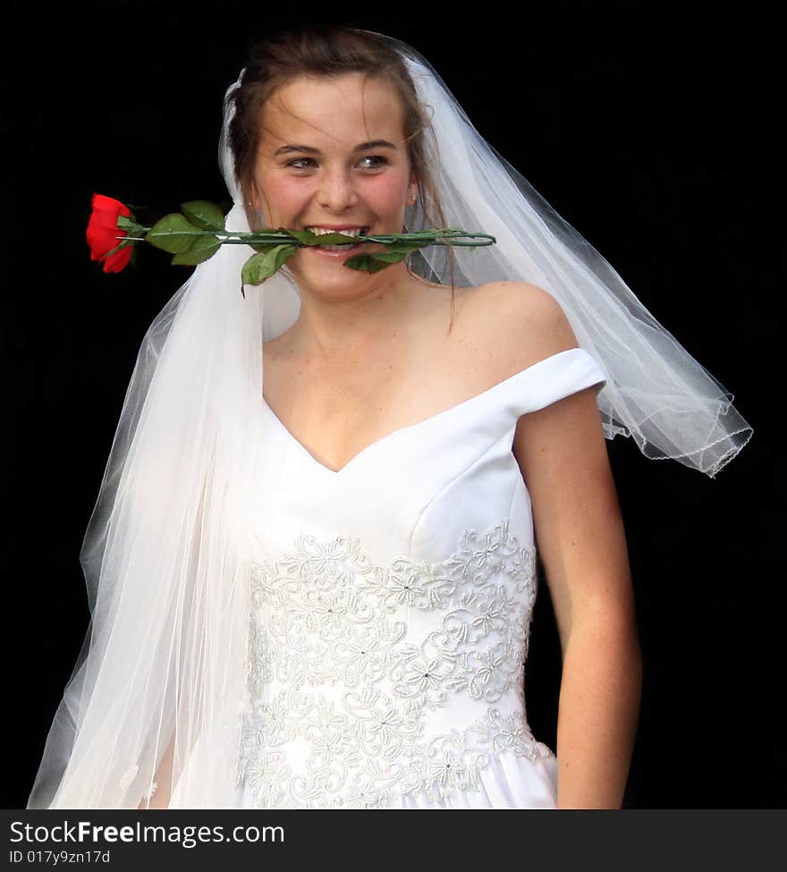 A beautiful young white caucasian teenager before her wedding with a happy expression on her face and a rose in her mouth looking at her future husband. A beautiful young white caucasian teenager before her wedding with a happy expression on her face and a rose in her mouth looking at her future husband