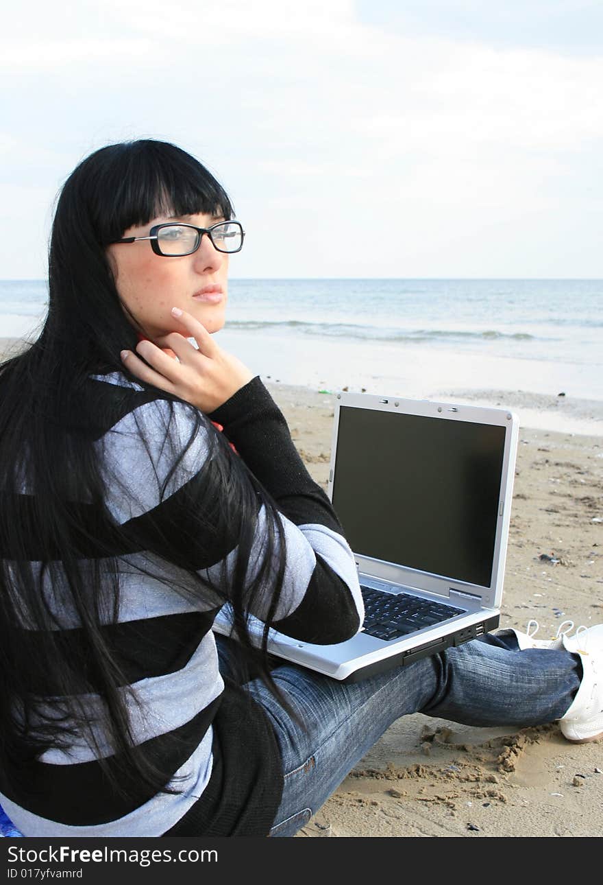 Young woman with computer at the beach. Young woman with computer at the beach