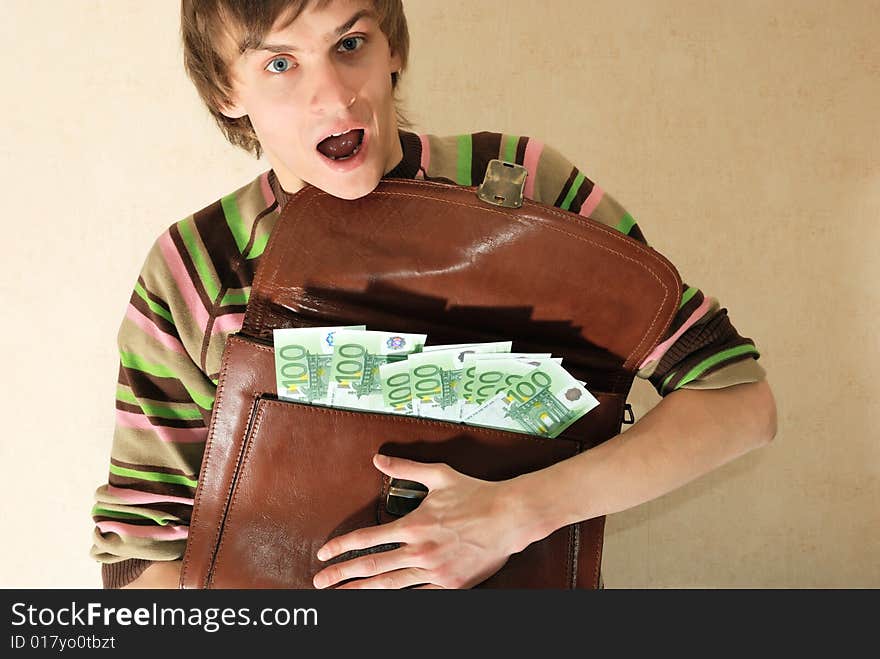 Young man in casual clothes with briefcase full of money. Young man in casual clothes with briefcase full of money