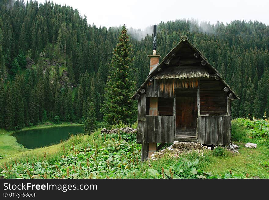 The wood cabin in Julian Alps with the small lake and forest against a background