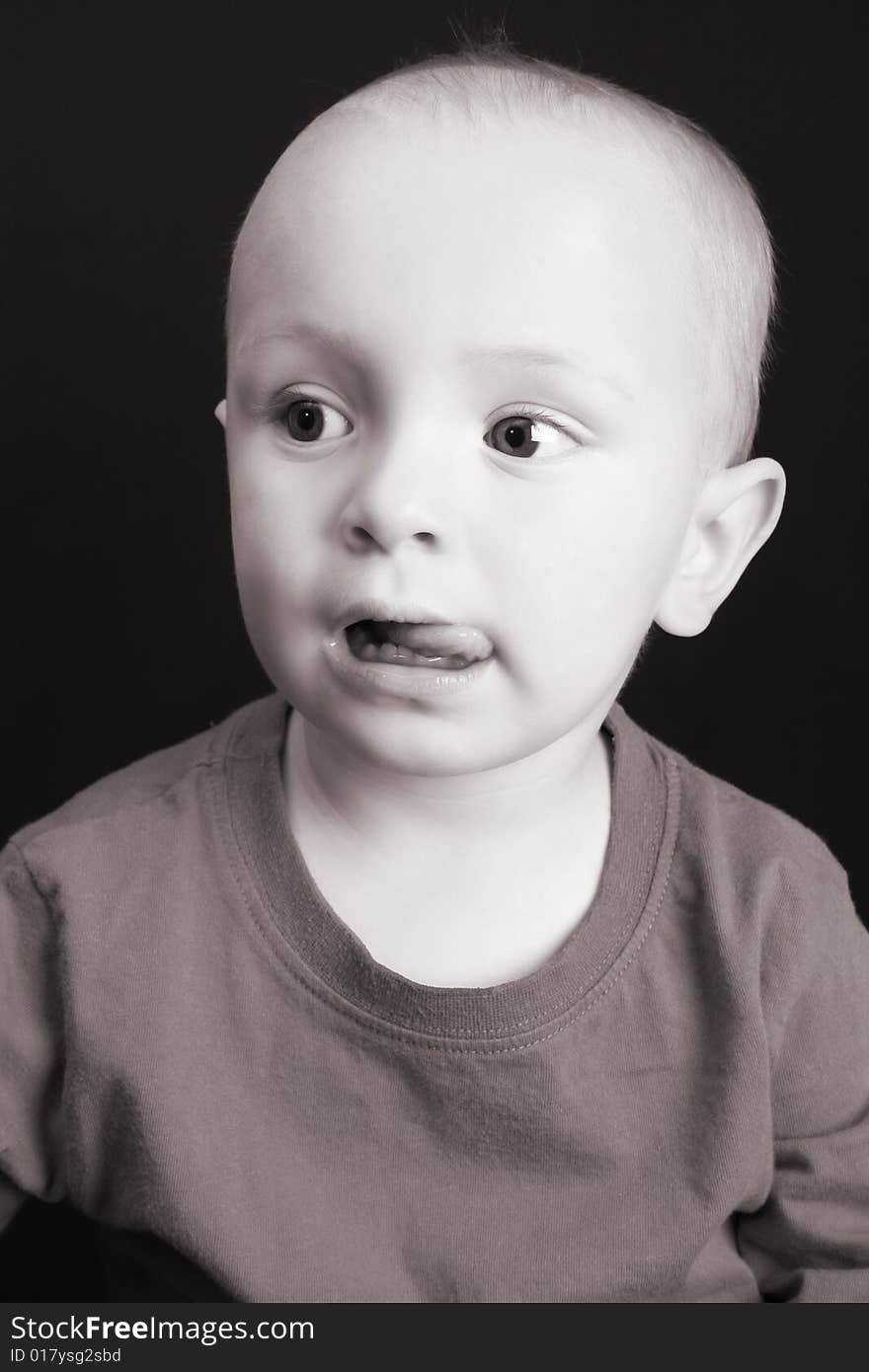 Blond toddler against a black background with a serious expression