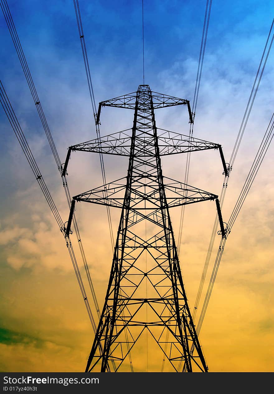 Silhouette of electricity pylon with blue and yellow sky