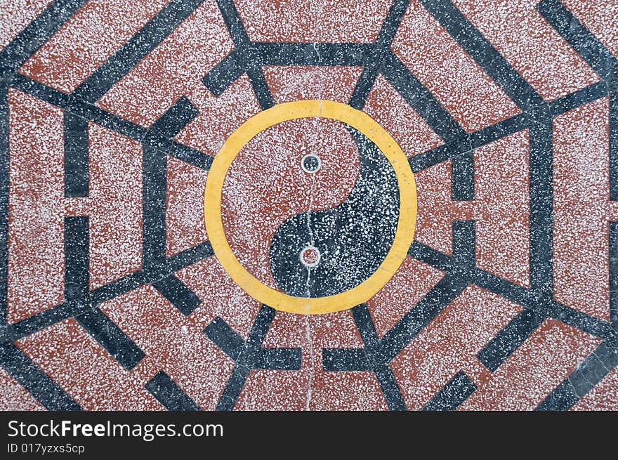 A yin yang Chinese symbol in black, yellow and red granite