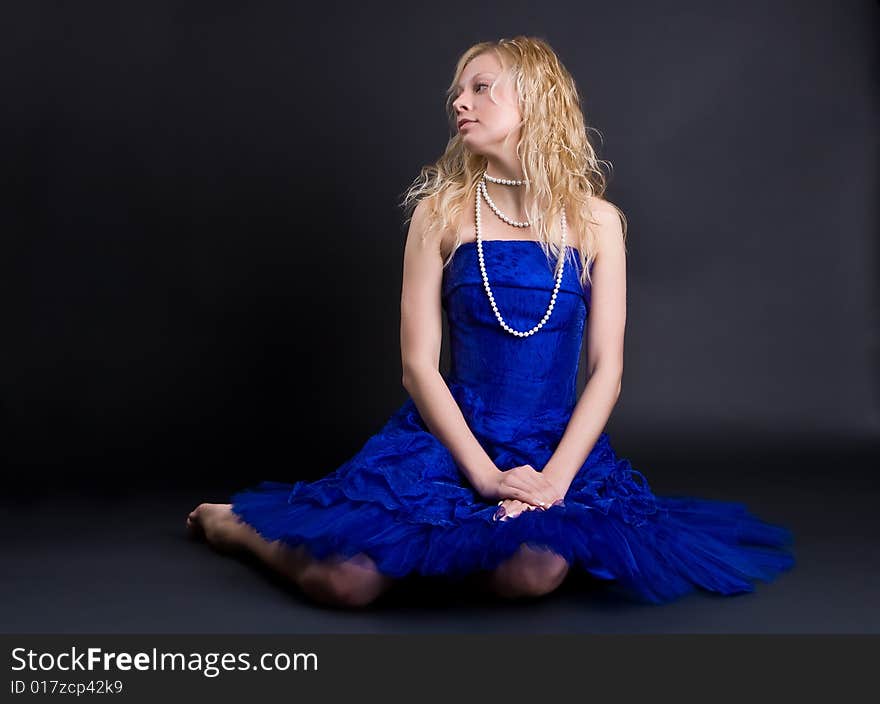 Beautiful girl in a dark blue dress and a pearl necklace on a black background. Beautiful girl in a dark blue dress and a pearl necklace on a black background