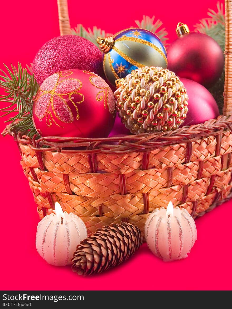 Burning candles at yellow basket with fruit and New Year's spheres on red background. Burning candles at yellow basket with fruit and New Year's spheres on red background