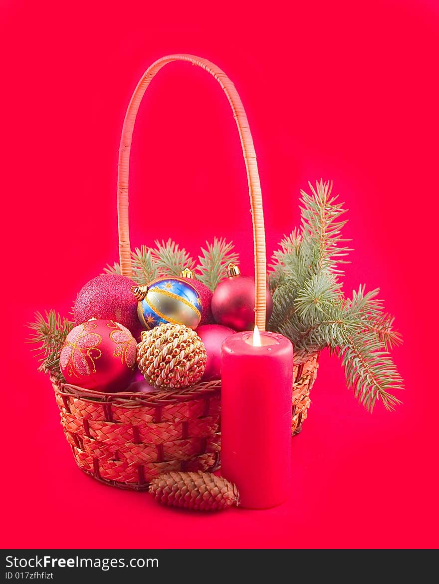 Red background with red candle and New Year's spheres in yellow basket with green branch