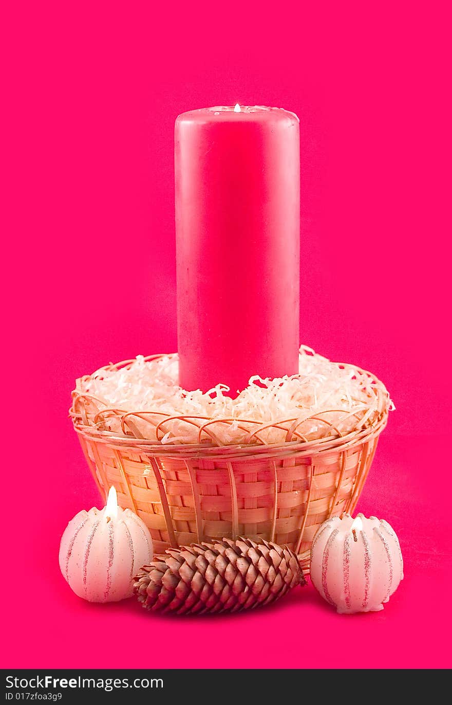 Burning candle in yellow basket and small candles on red background. Burning candle in yellow basket and small candles on red background