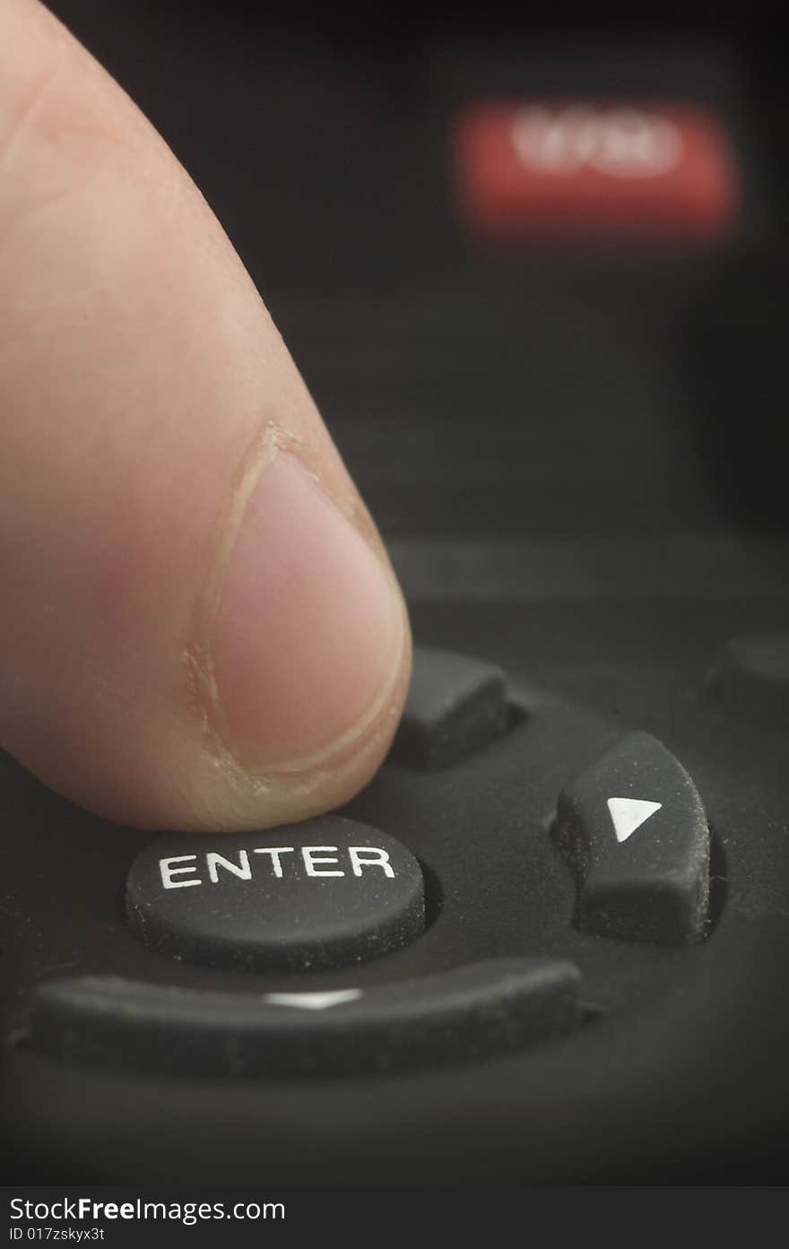 Man finger pushing ENTER on a black remote control