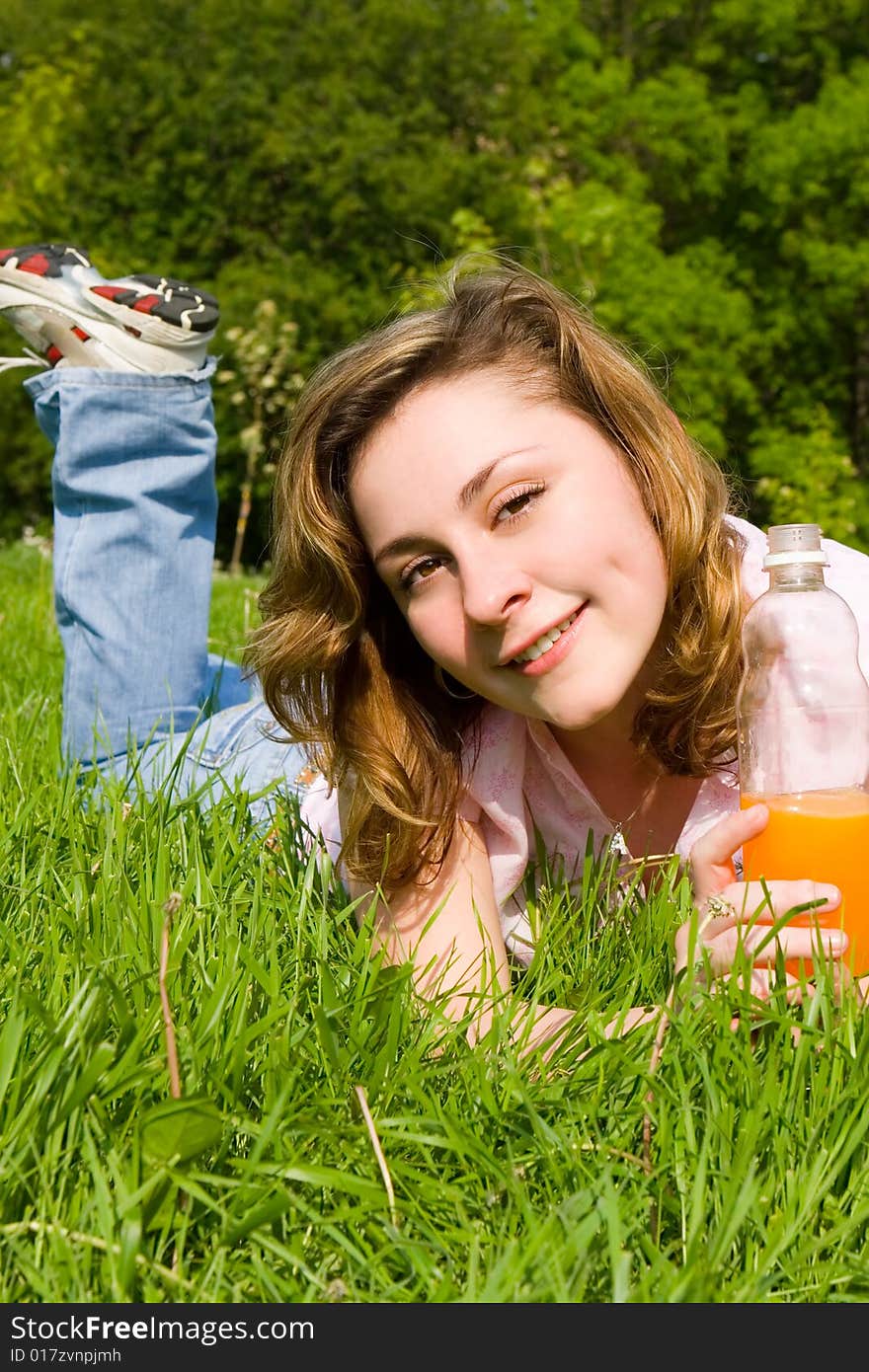 Pretty woman drinking juice on the summer glade