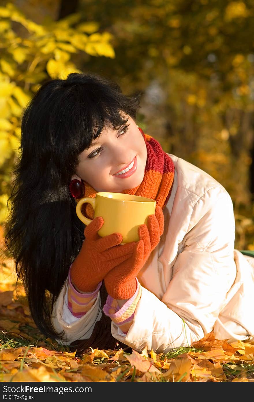 Young pretty woman with tea cup in the autumn park