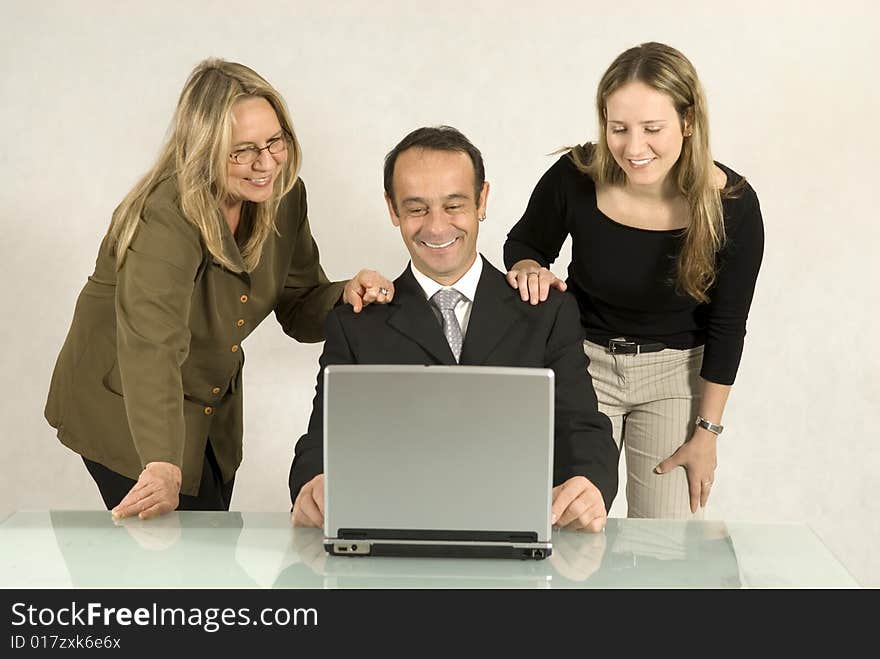 Three people are in a business meeting. They are smiling and looking at the screen of the laptop. Horizontally framed shot. Three people are in a business meeting. They are smiling and looking at the screen of the laptop. Horizontally framed shot.