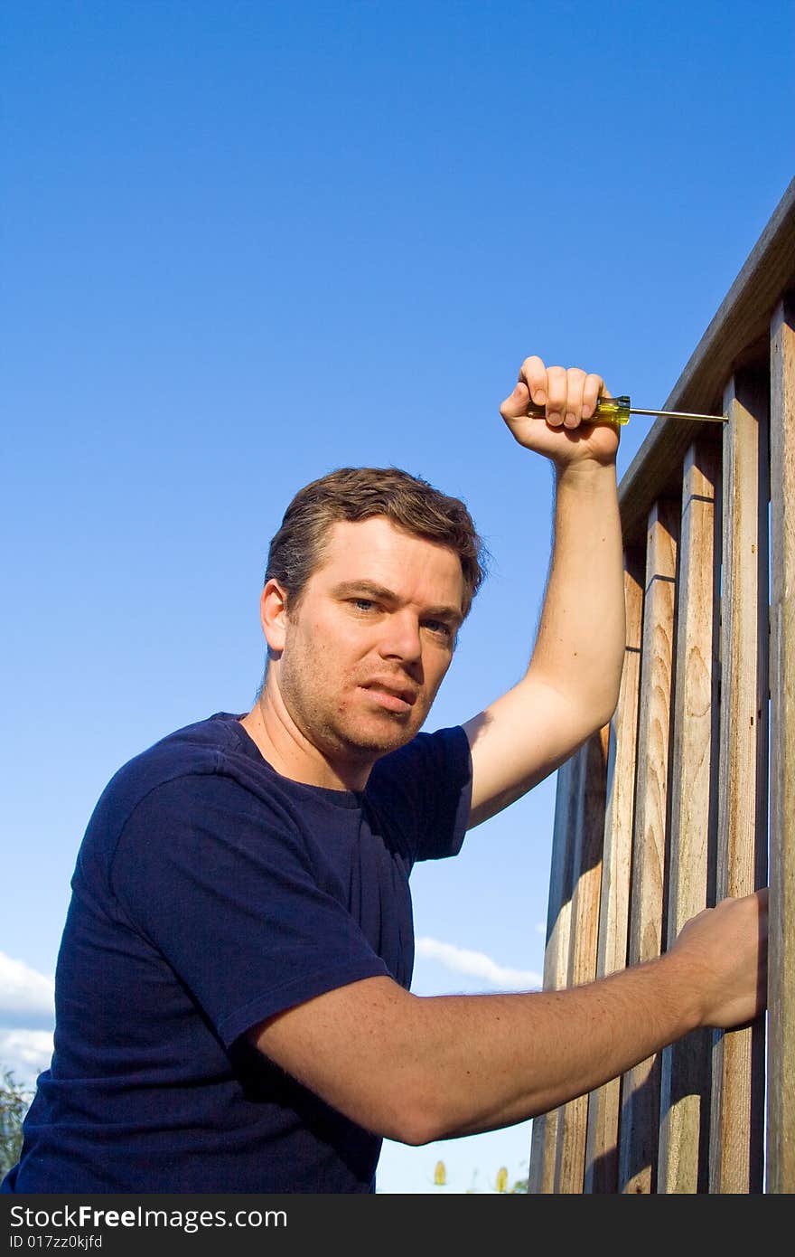 Angry man using screwdriver to fix porch. Vertically framed photo. Angry man using screwdriver to fix porch. Vertically framed photo.