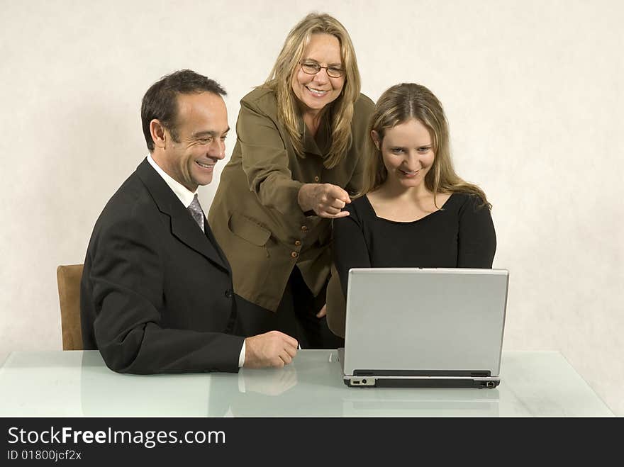 Three people are in a business meeting. They are smiling and looking at the screen of the laptop. Horizontally framed shot. Three people are in a business meeting. They are smiling and looking at the screen of the laptop. Horizontally framed shot.