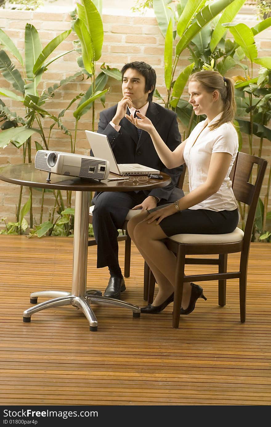 Man and woman with a projector and a laptop. They are seated and smiling . Vertically framed photo. Man and woman with a projector and a laptop. They are seated and smiling . Vertically framed photo.