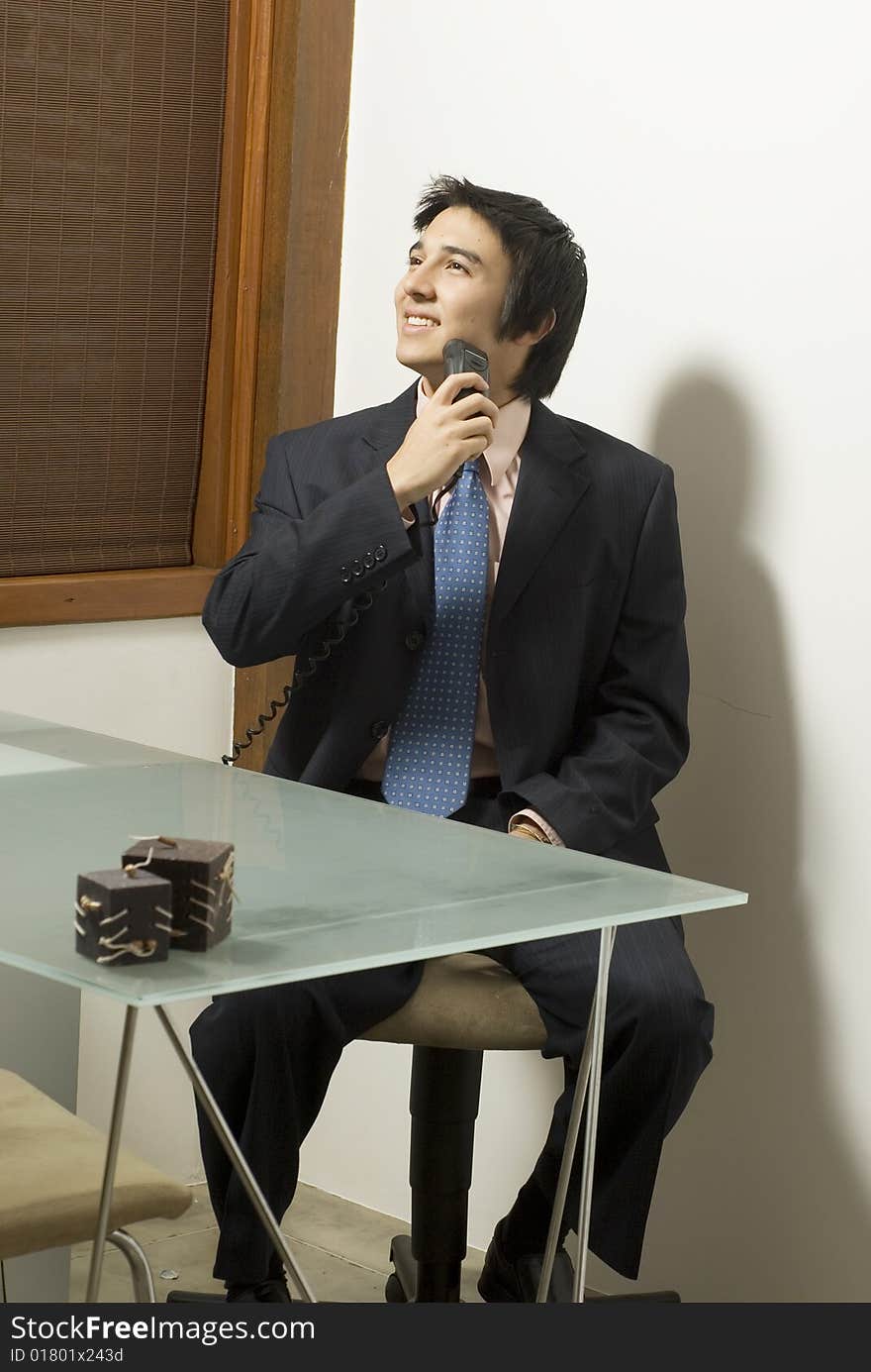 Smiling man in a suit shaving as he sits at a table. Vertically framed photo. Smiling man in a suit shaving as he sits at a table. Vertically framed photo.