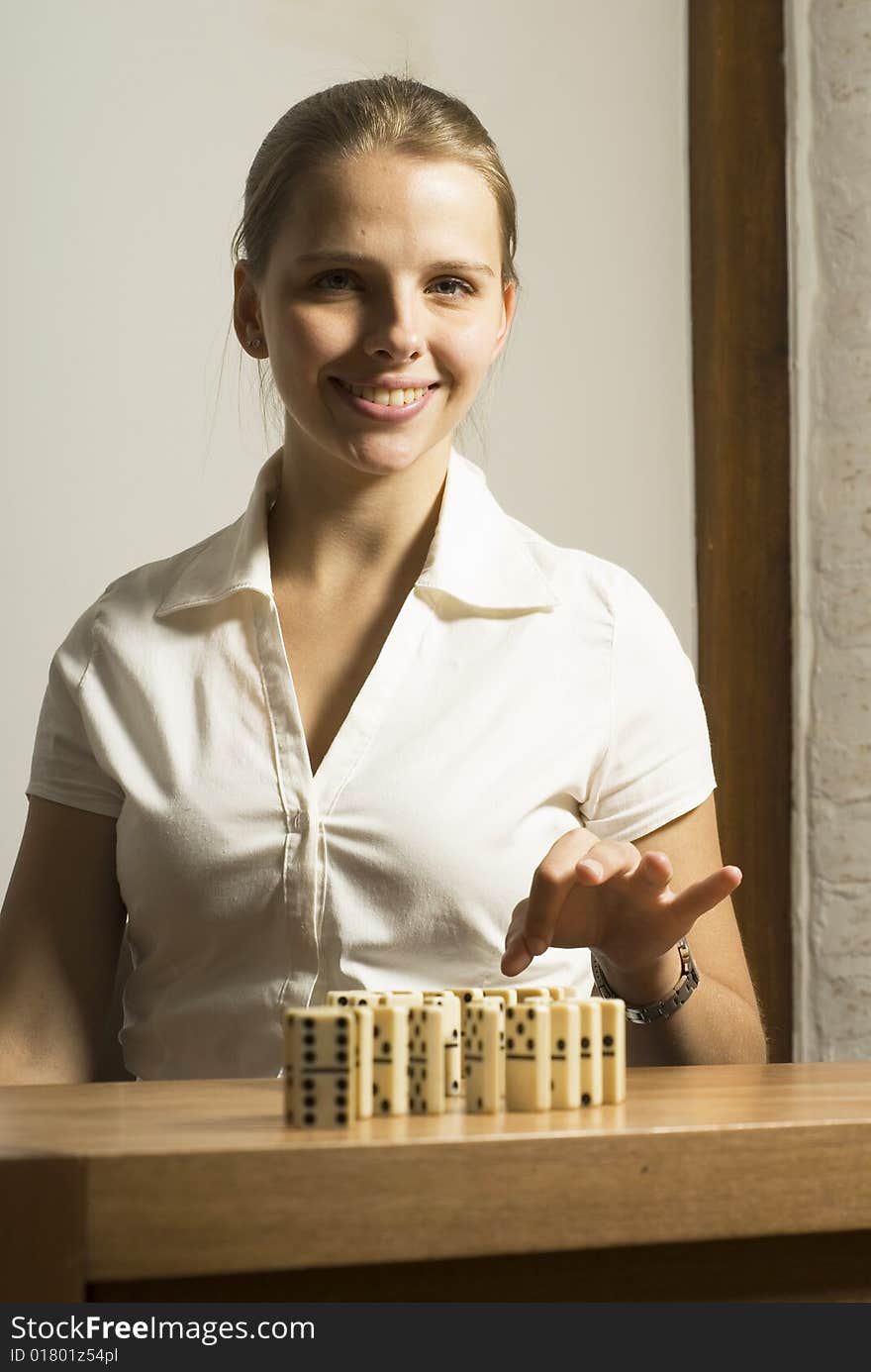 Smiling young woman seated at desk playing dominos. Vertically framed photo. Smiling young woman seated at desk playing dominos. Vertically framed photo.