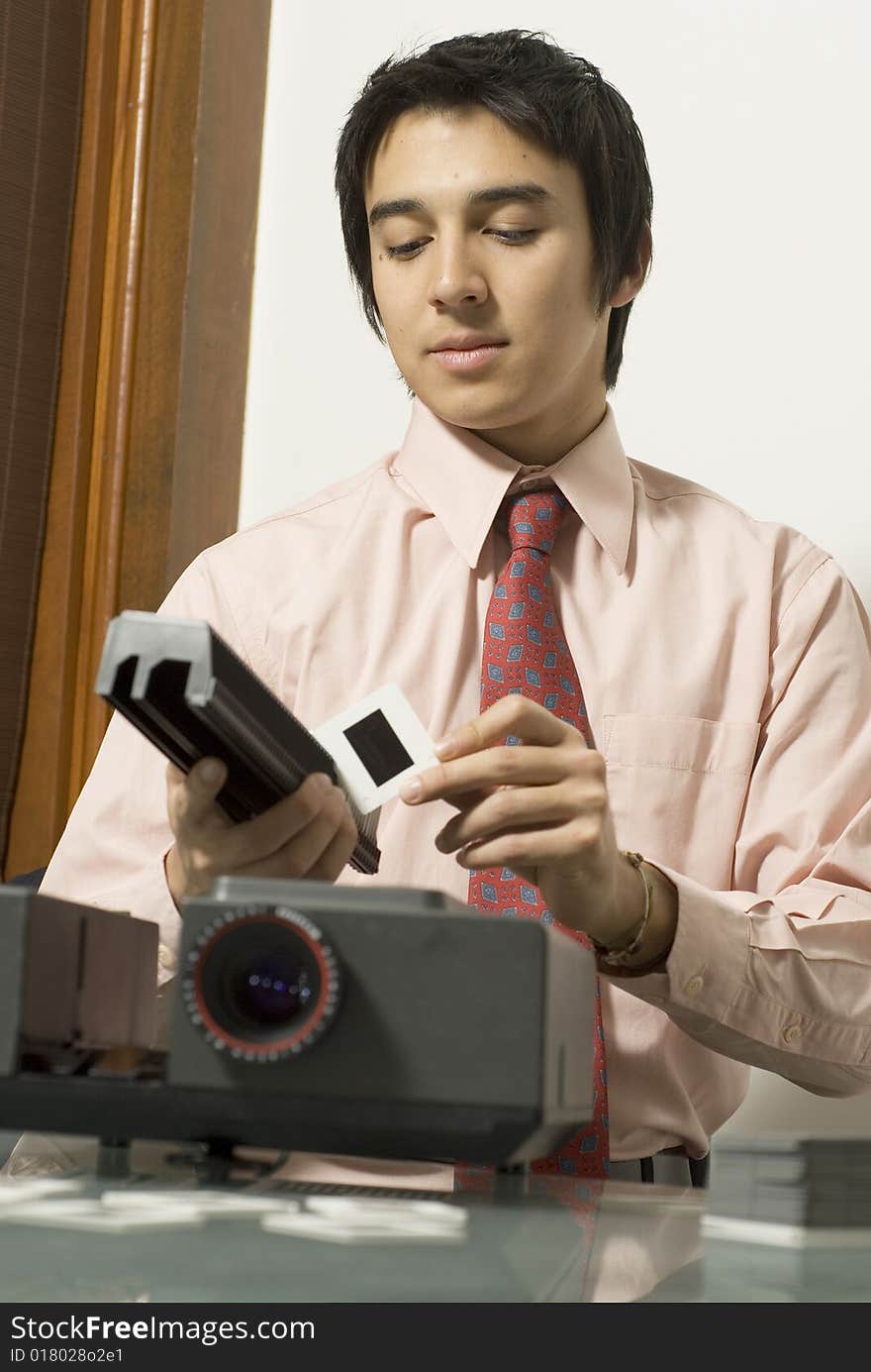 Man wearing a serious expression on his face as he looks at a slide next to a projector. Vertically framed photo. Man wearing a serious expression on his face as he looks at a slide next to a projector. Vertically framed photo.