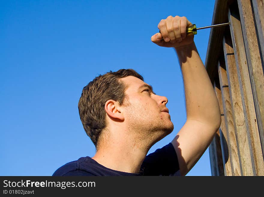 Man using screwdriver to fix porch. Horizontally framed photo. Man using screwdriver to fix porch. Horizontally framed photo.