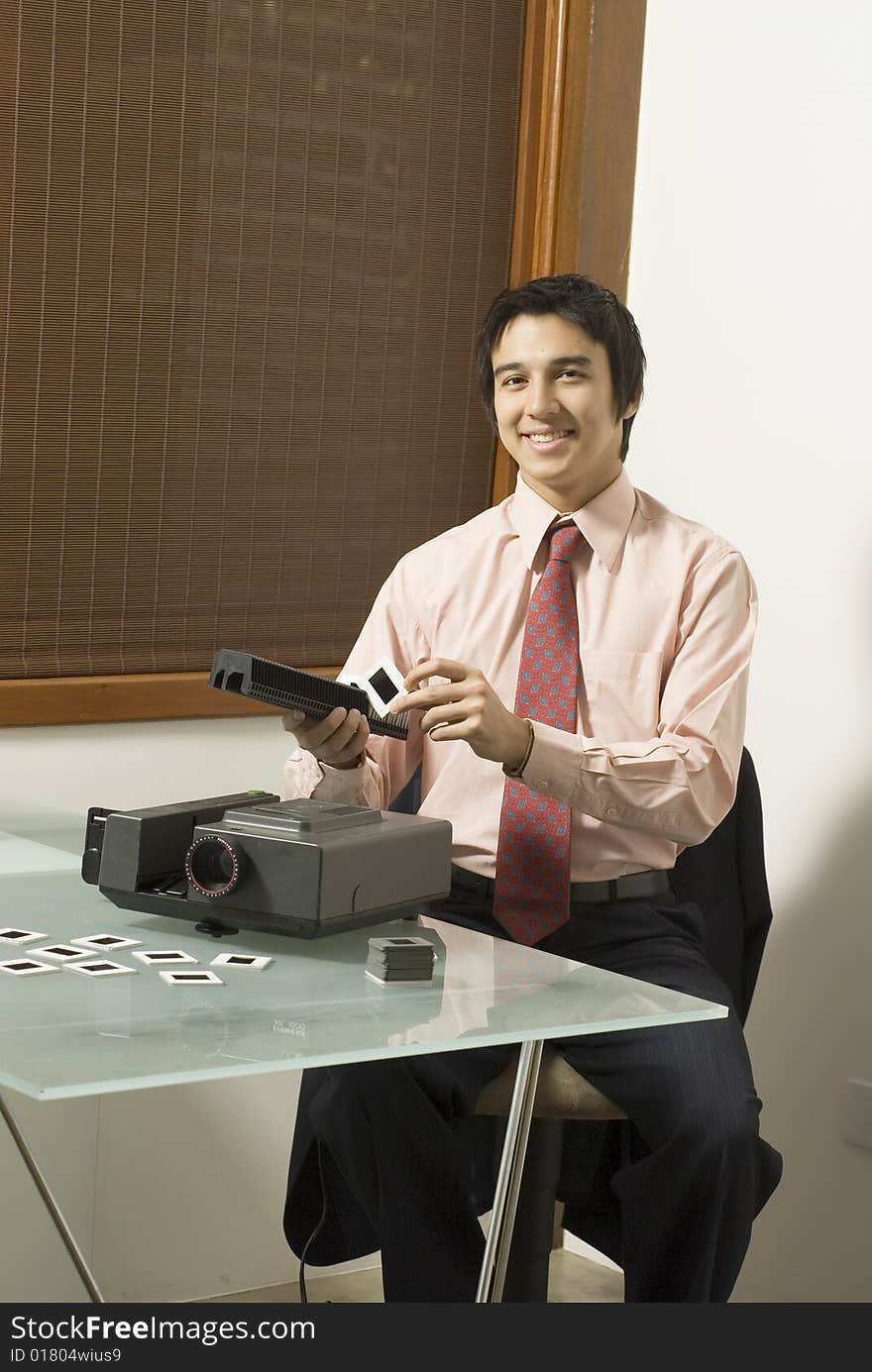 Man smiling as he looks at a slide next to a projector. Vertically framed photo. Man smiling as he looks at a slide next to a projector. Vertically framed photo.