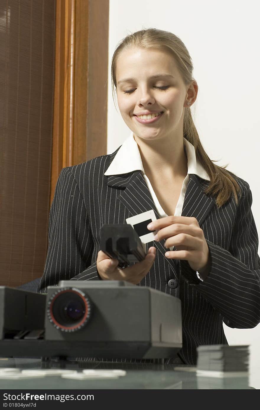 Woman  smiling as she places slides in  a slide show projector. Vertically framed photo. Woman  smiling as she places slides in  a slide show projector. Vertically framed photo.