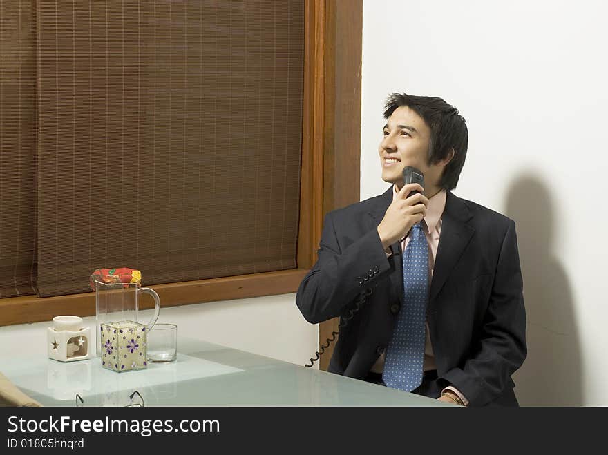 Smiling man in a suit shaving as he sits at a table with a pitcher and a candle on it. Horizontally framed photo. Smiling man in a suit shaving as he sits at a table with a pitcher and a candle on it. Horizontally framed photo.