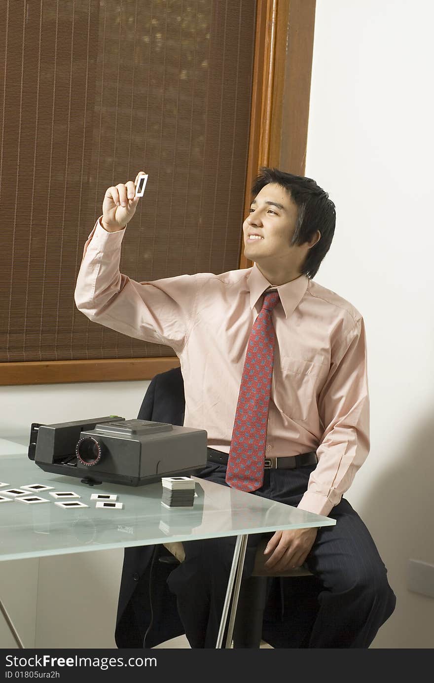 Man smiling as he looks at a slide  from a slide show projector. Vertically framed photo. Man smiling as he looks at a slide  from a slide show projector. Vertically framed photo.