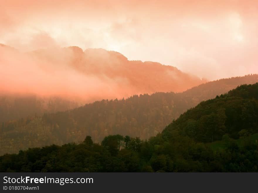 Misty and cloudy mountains silhouette with sunset pink skies. Misty and cloudy mountains silhouette with sunset pink skies